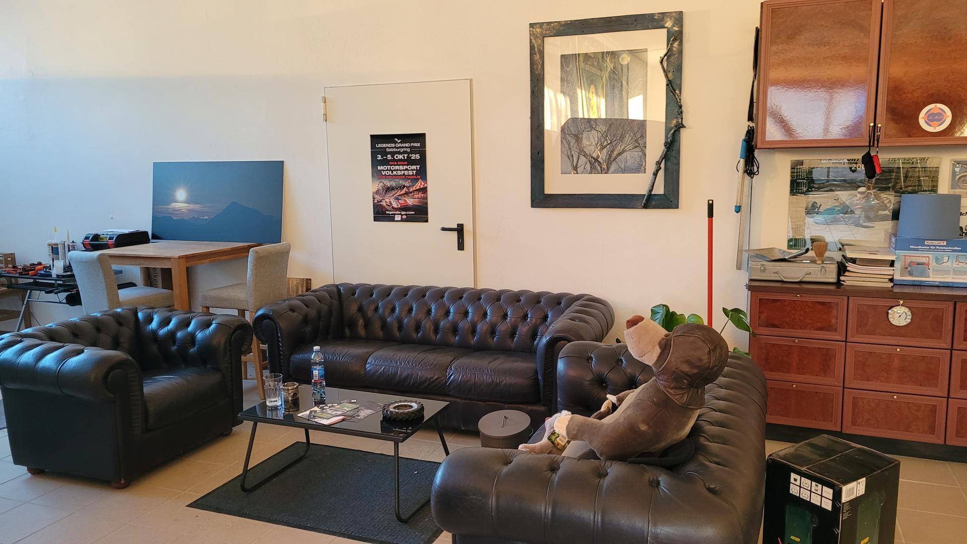 Gemütlicher Wohnbereich mit dunklen Ledersofas, einem Couchtisch und hellen Fliesenböden.