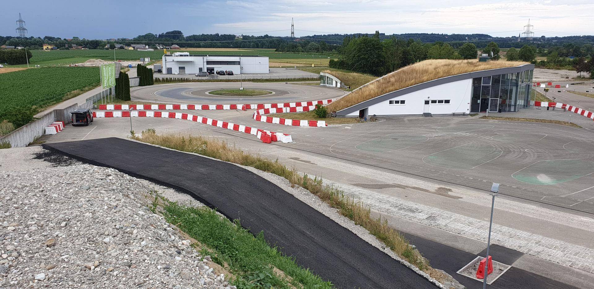 Weitläufige Ansicht des Fahrtechnikzentrums mit verschiedenen Teststrecken und dem Hauptgebäude.