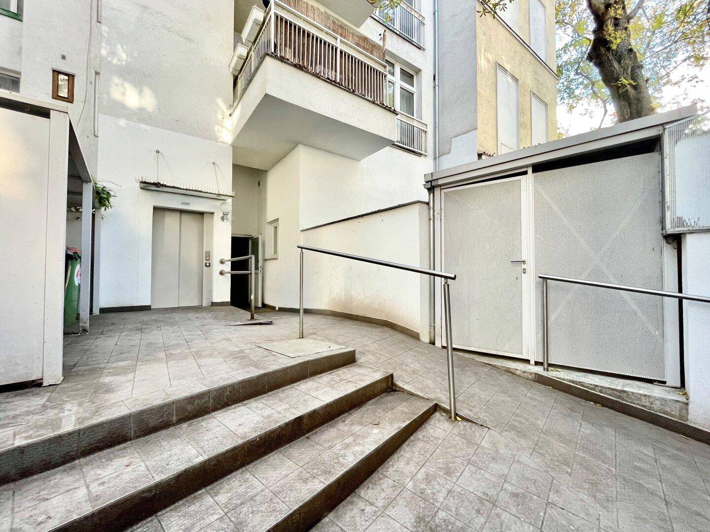Eingangsbereich des Gebäudes mit Rampe, Treppe und Aufzug für barrierefreien Zugang.