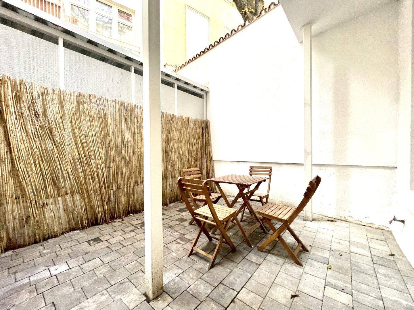 Gemütliche Terrasse mit Holztisch und Stühlen, umgeben von einem natürlichen Sichtschutz.