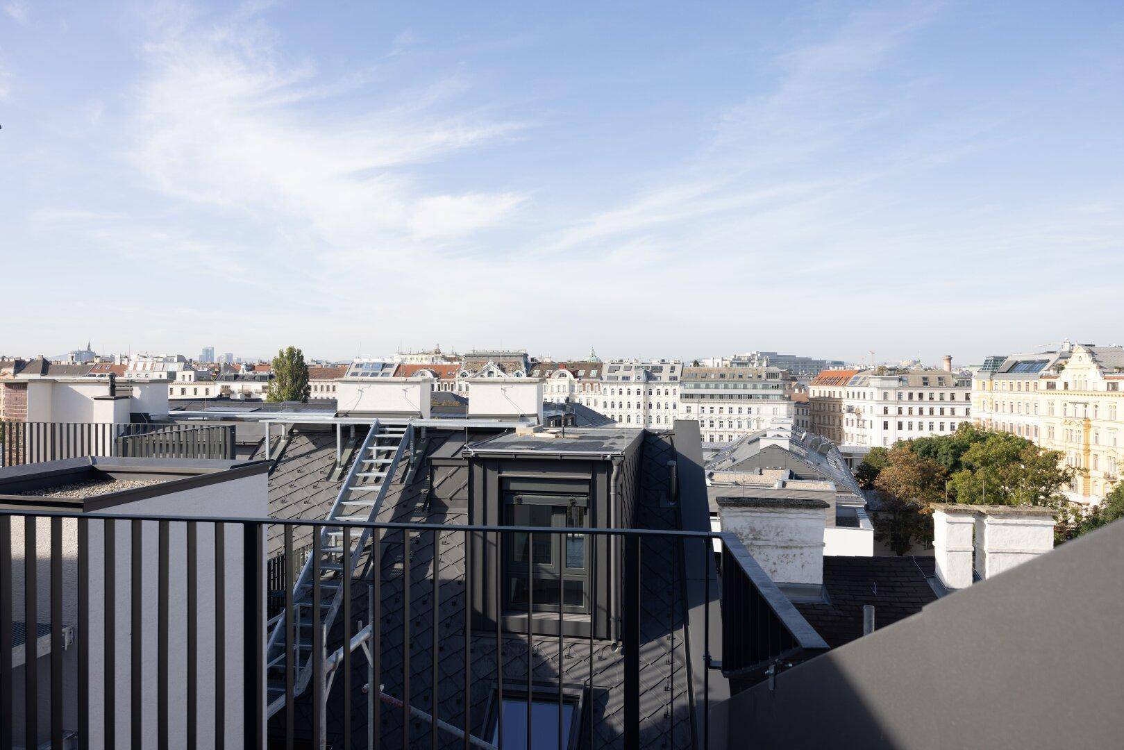 Panoramablick über die Dächer der Stadt von einer Dachterrasse, mit klarem Himmel.