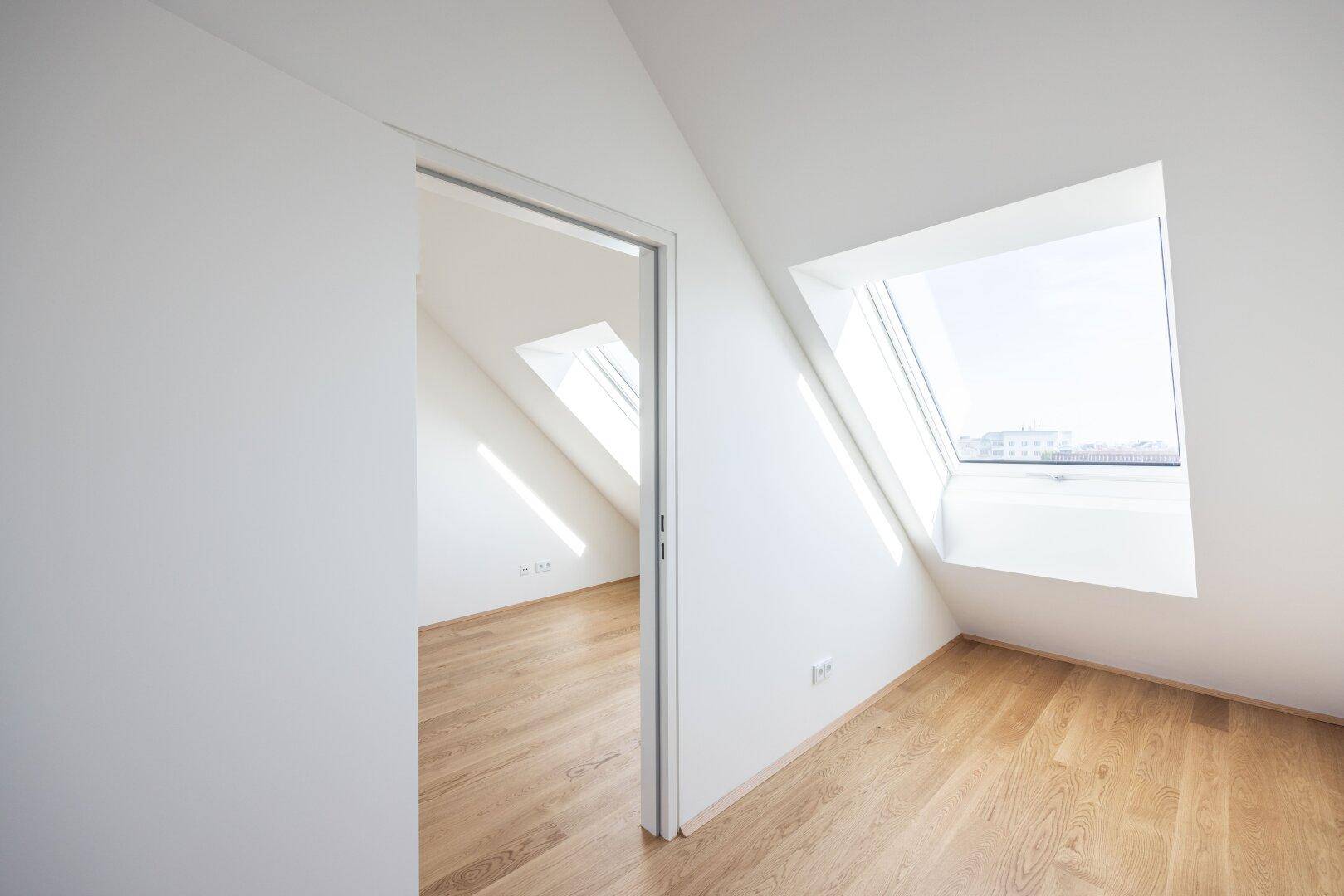 Heller Raum im Dachgeschoss mit Holzboden und großem Dachfenster, das viel Licht spendet.