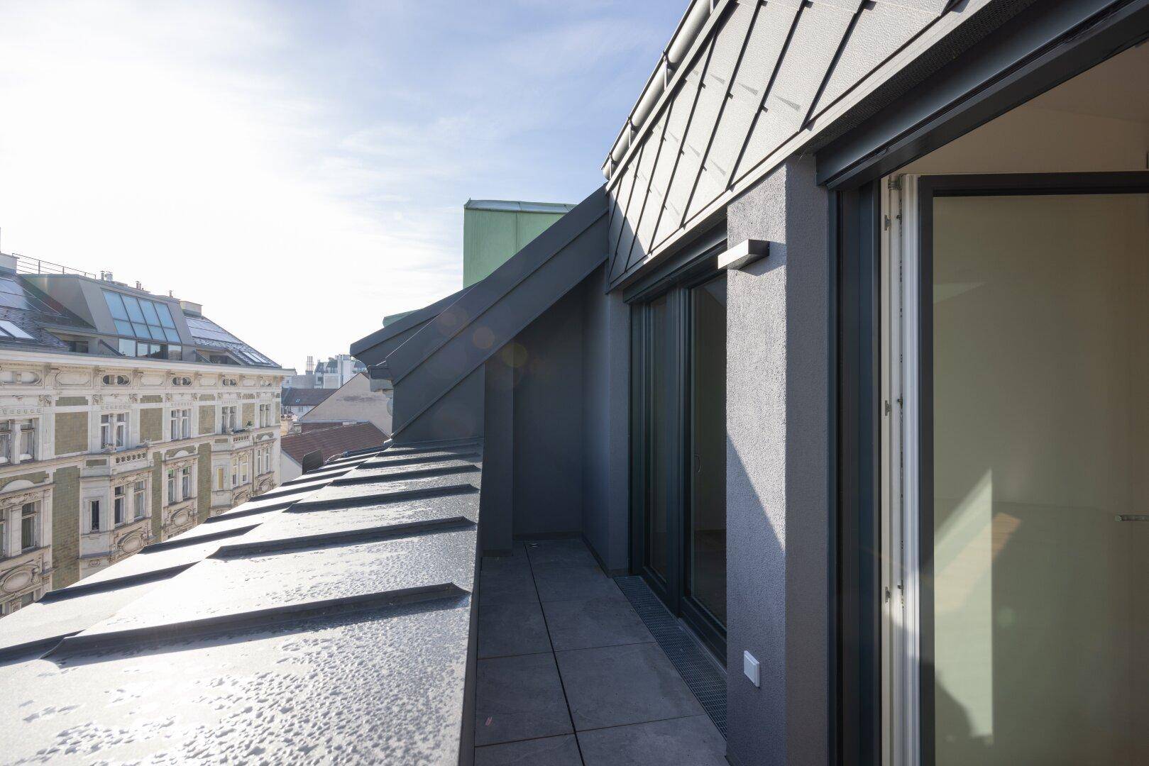 Schmaler Balkon mit Blick auf die umliegenden Gebäude und Dächer der Stadt.