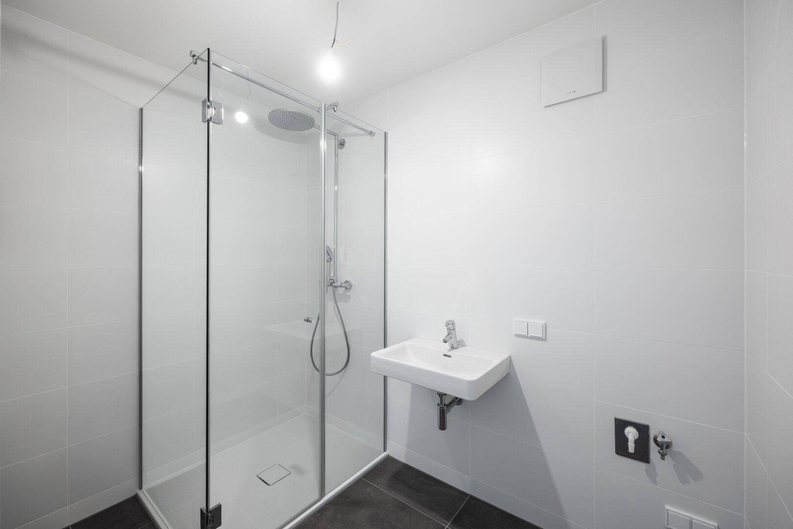 Modernes Badezimmer mit begehbarer Dusche, Einzelwaschbecken und weißen Fliesen.