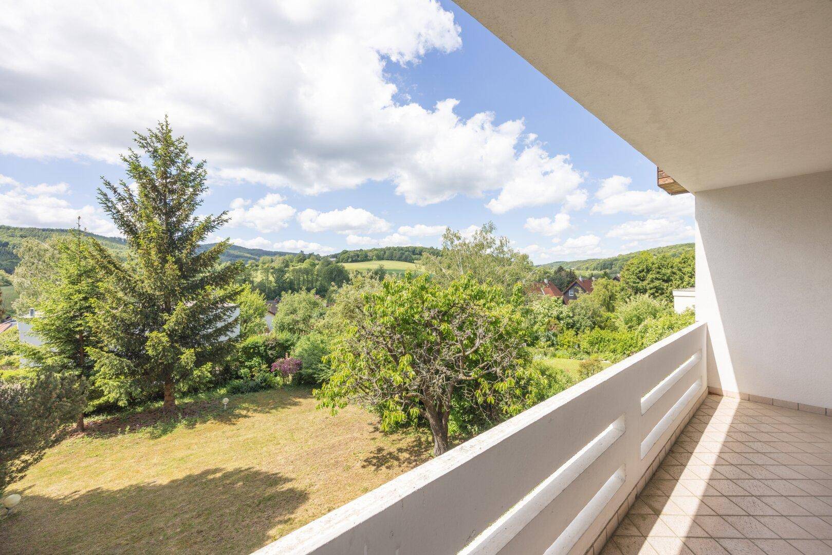 Balkon mit weitem Blick über die grüne Hügellandschaft und den Garten.