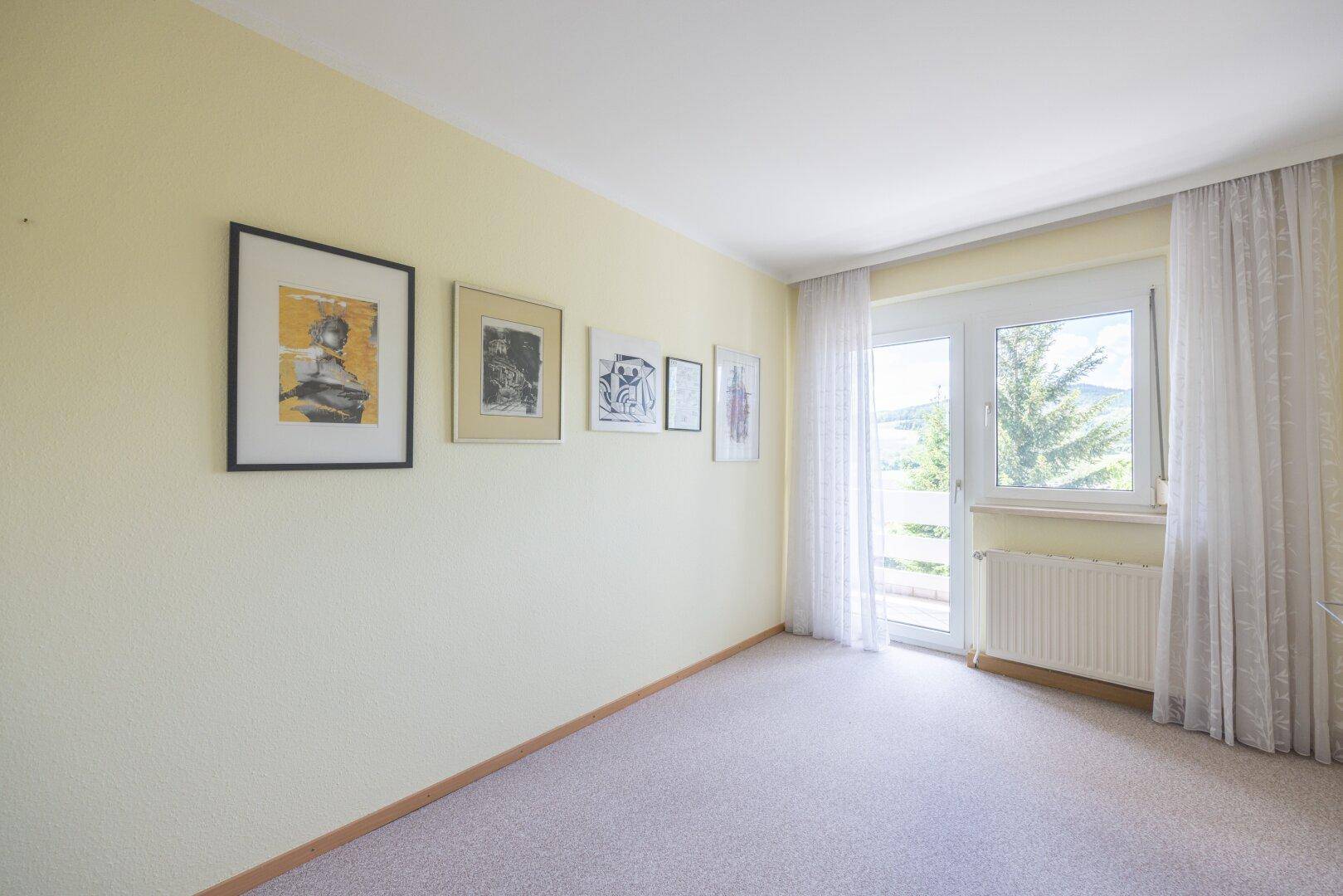 Heller Raum mit Teppichboden und Zugang zu einem Balkon, ideal als Schlaf- oder Arbeitszimmer.