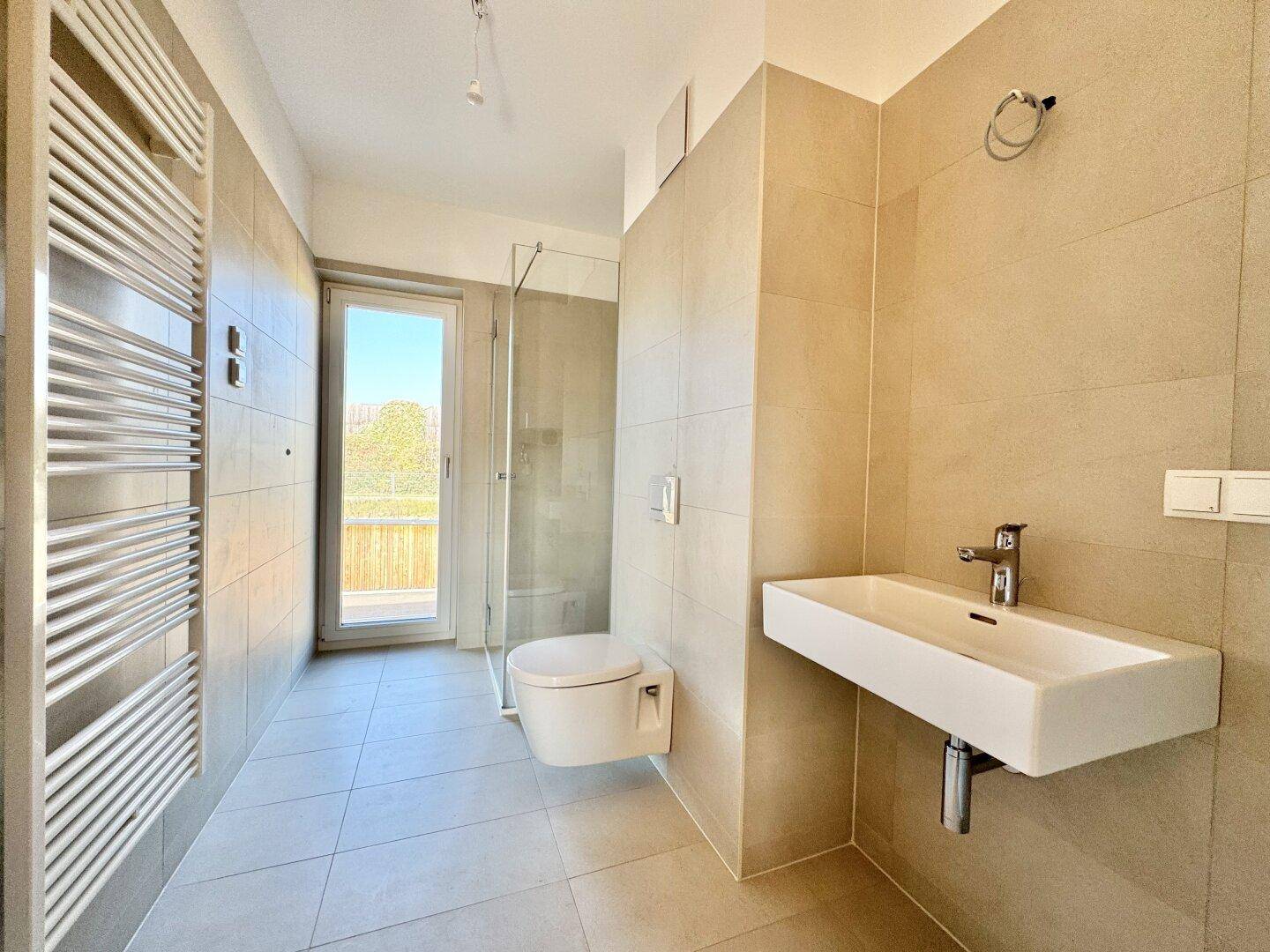 Modernes Badezimmer mit begehbarer Dusche, Wand-WC, Einzelwaschbecken und beheiztem Handtuchhalter.