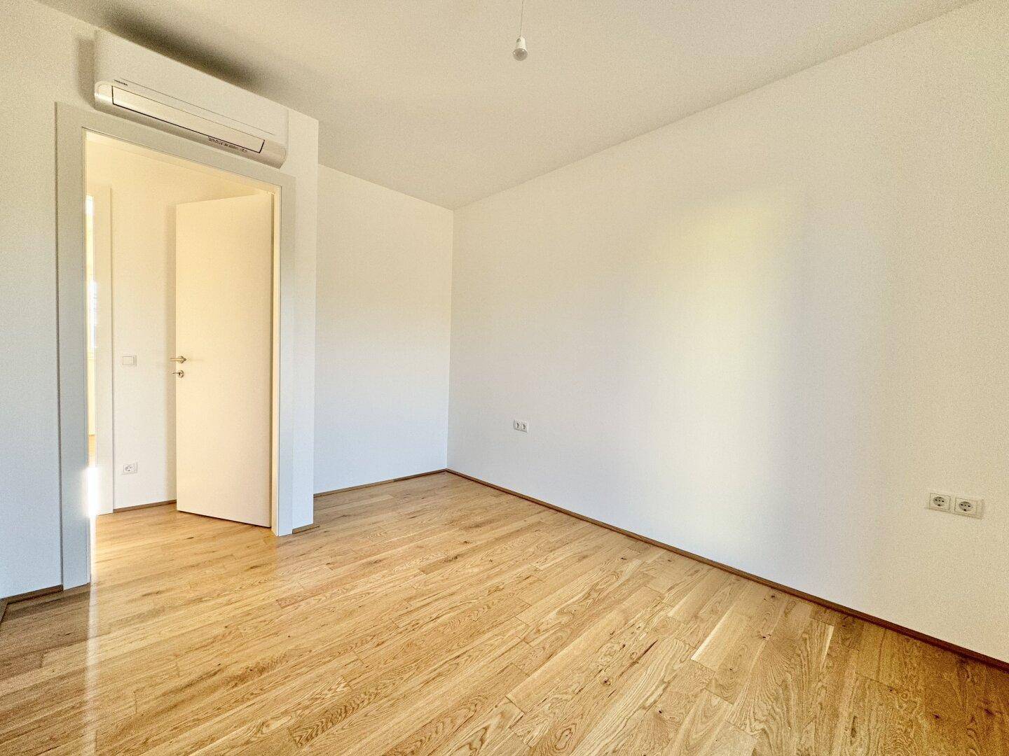 Helles Zimmer mit Eichenparkett und Klimaanlage, bietet Komfort und vielseitige Nutzungsmöglichkeiten.