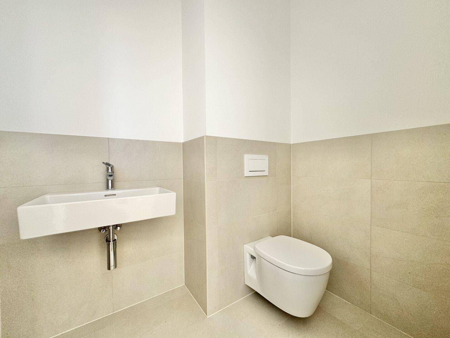 Modernes Gäste-WC mit Wand-WC und stilvollem Einzelwaschbecken, in neutralen Farbtönen gehalten.