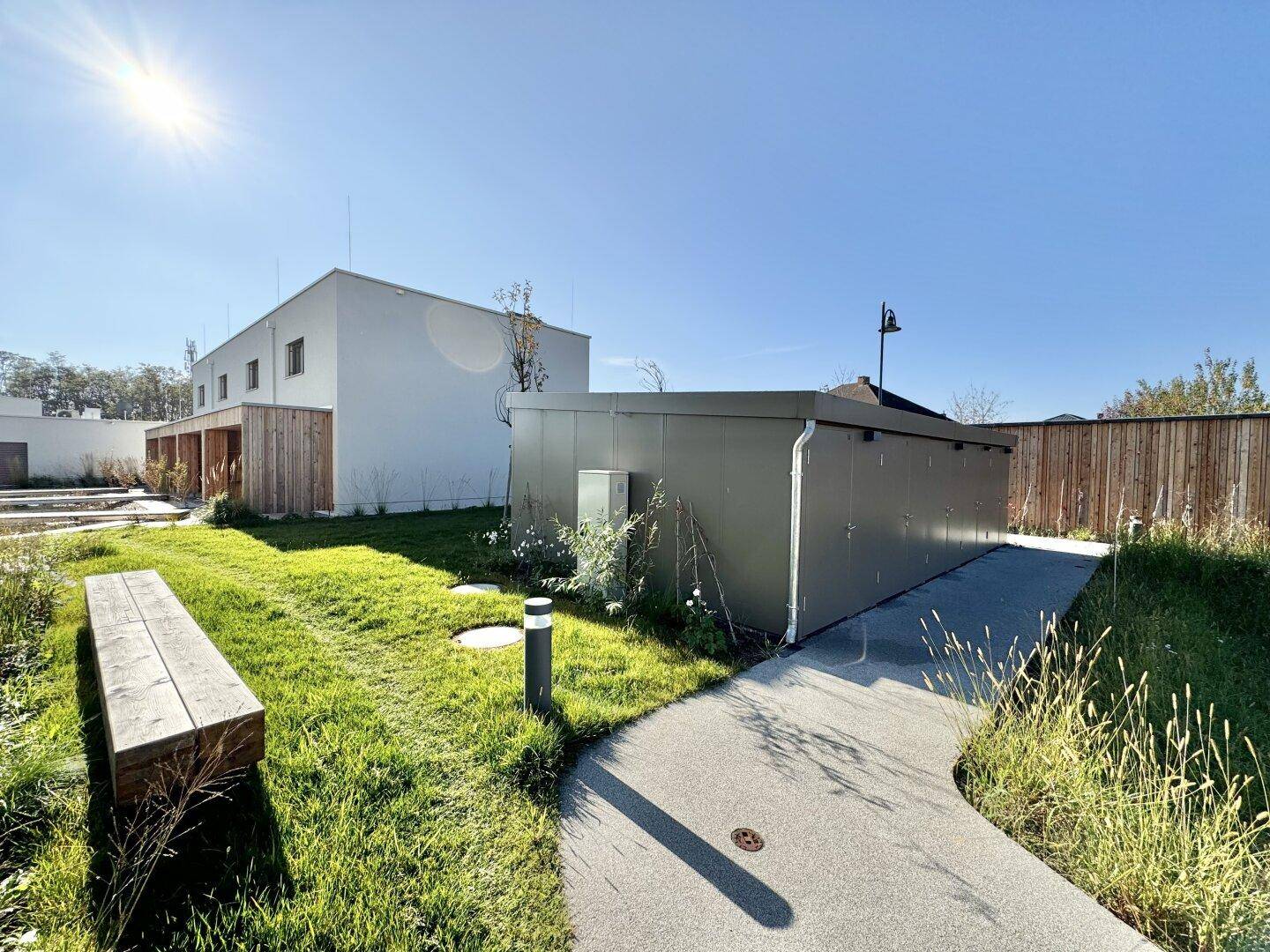 Gepflegter Gartenbereich mit Sitzbank und einem praktischen Schuppen, umgeben von Grünflächen.