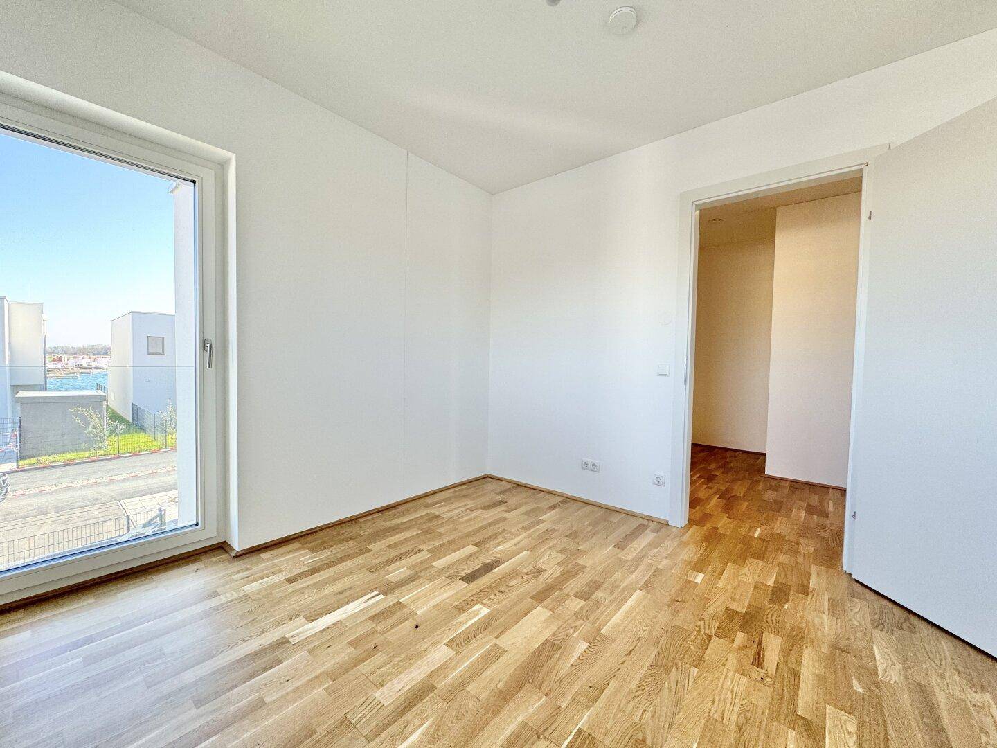 Heller Raum mit Parkettboden und Zugang zu einem Außenbereich.