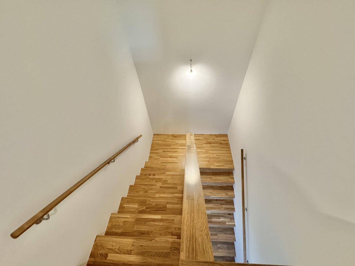 Elegante Holztreppe mit schlichtem Geländer, die zu den oberen Etagen führt.