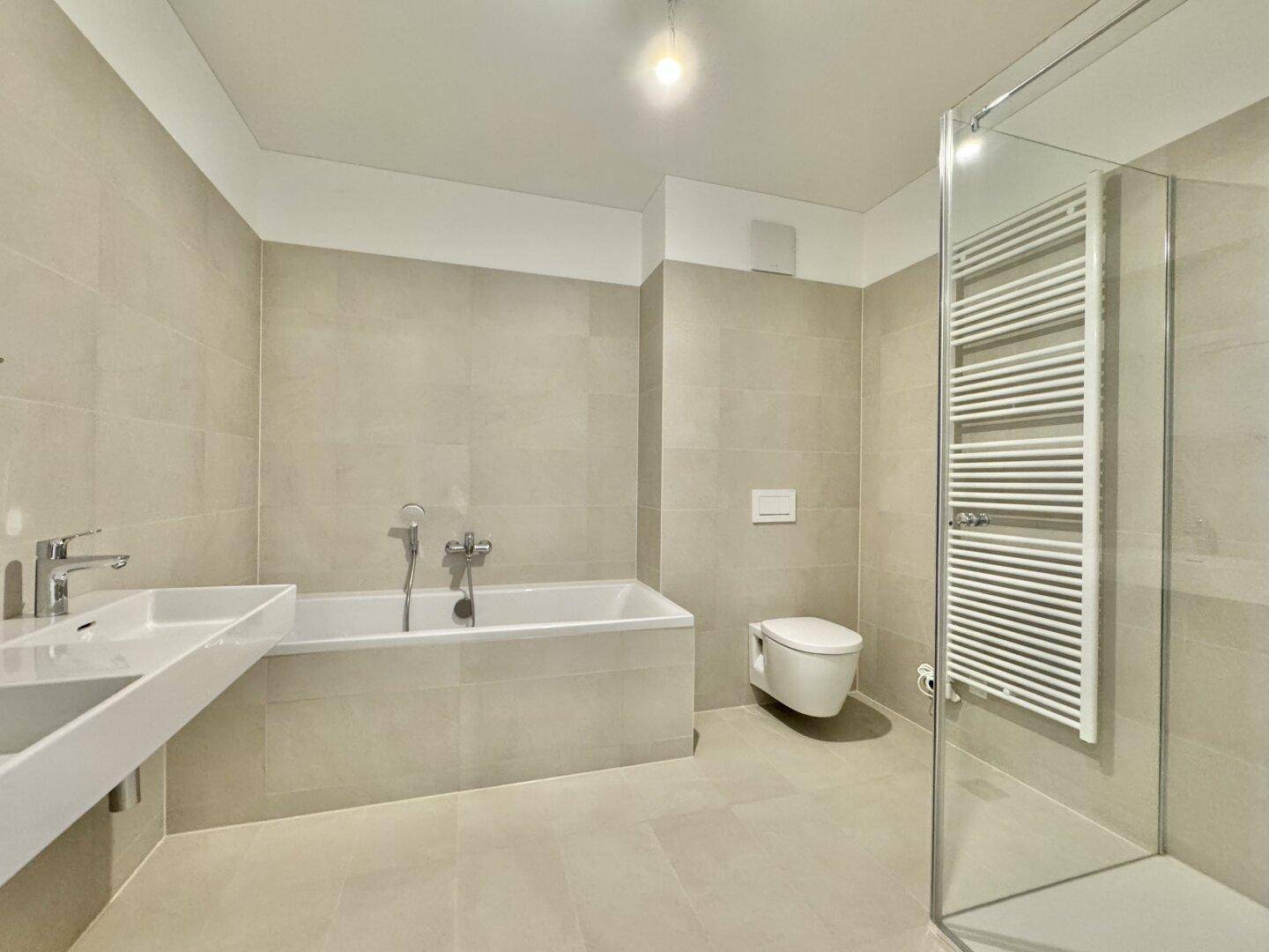 Modernes Badezimmer mit Badewanne, Dusche, Doppelwaschbecken und beheiztem Handtuchhalter.