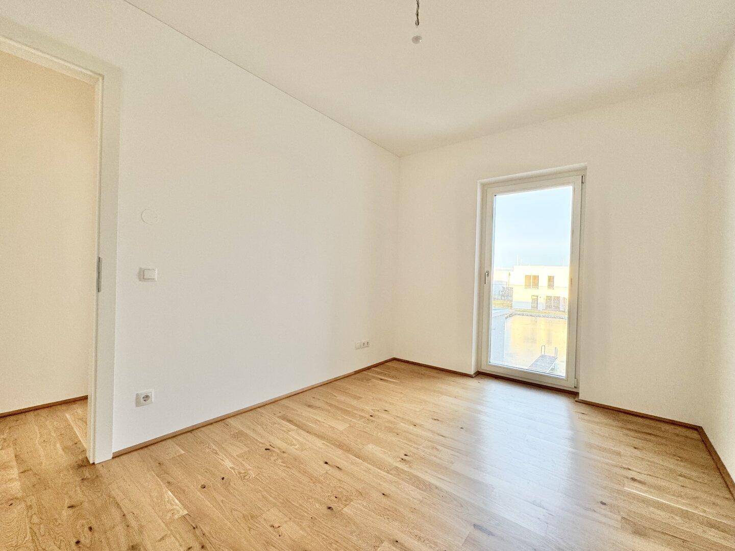 Geräumiges Zimmer mit hellem Parkettboden und weiß gestrichenen Wänden, bereit zur Einrichtung.