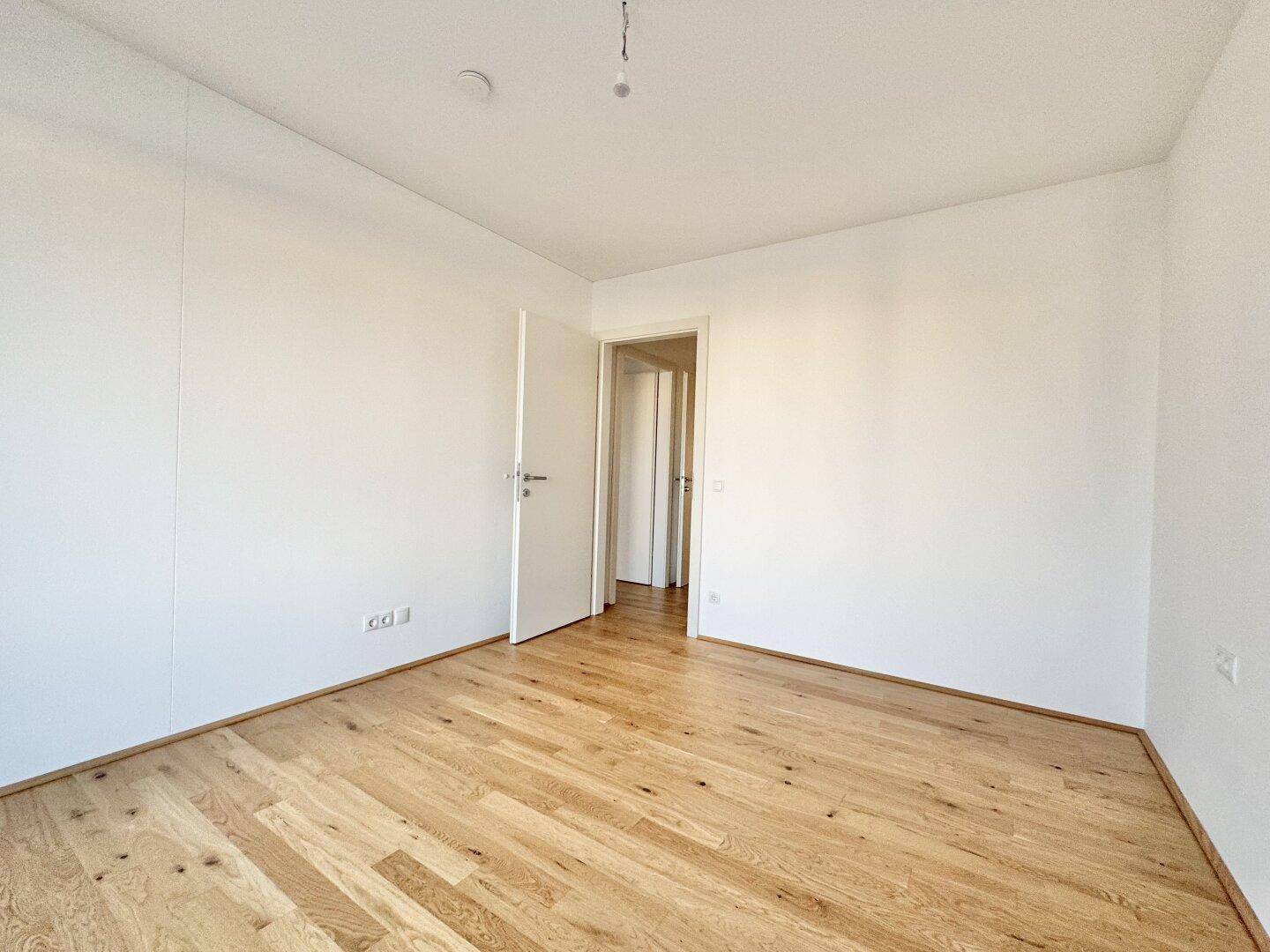 Helles Zimmer mit Eichenparkettboden und weiß gestrichenen Wänden, ideal für individuelle Gestaltung.