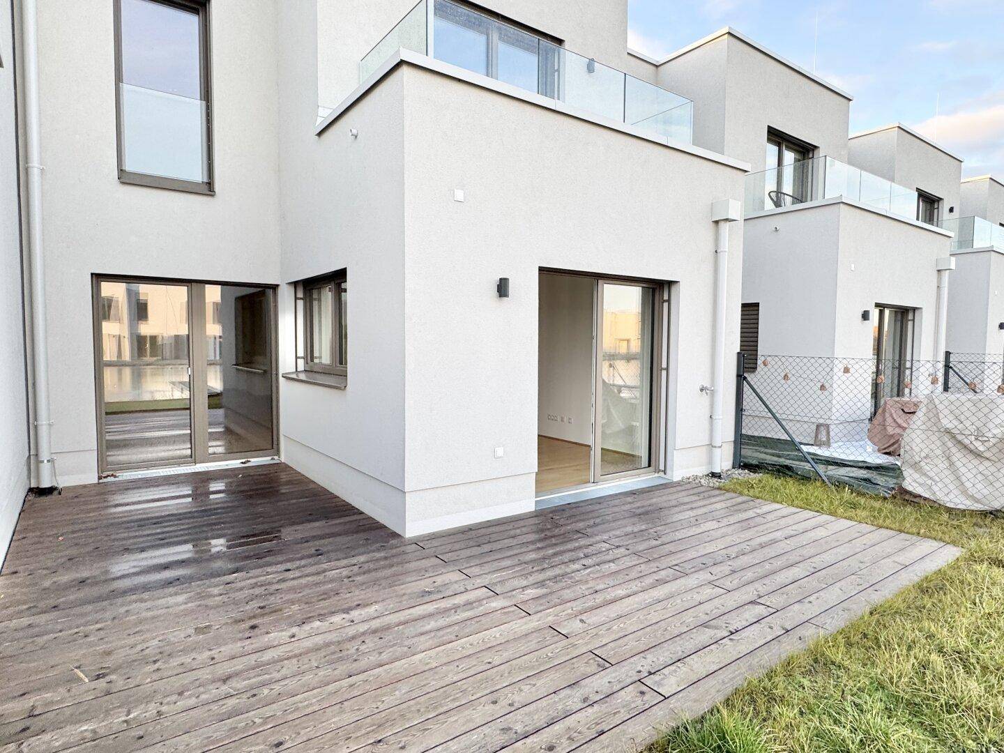 Moderne Reihenhäuser von hinten mit großzügigen Holzterrassen und Zugang zu den Gärten.