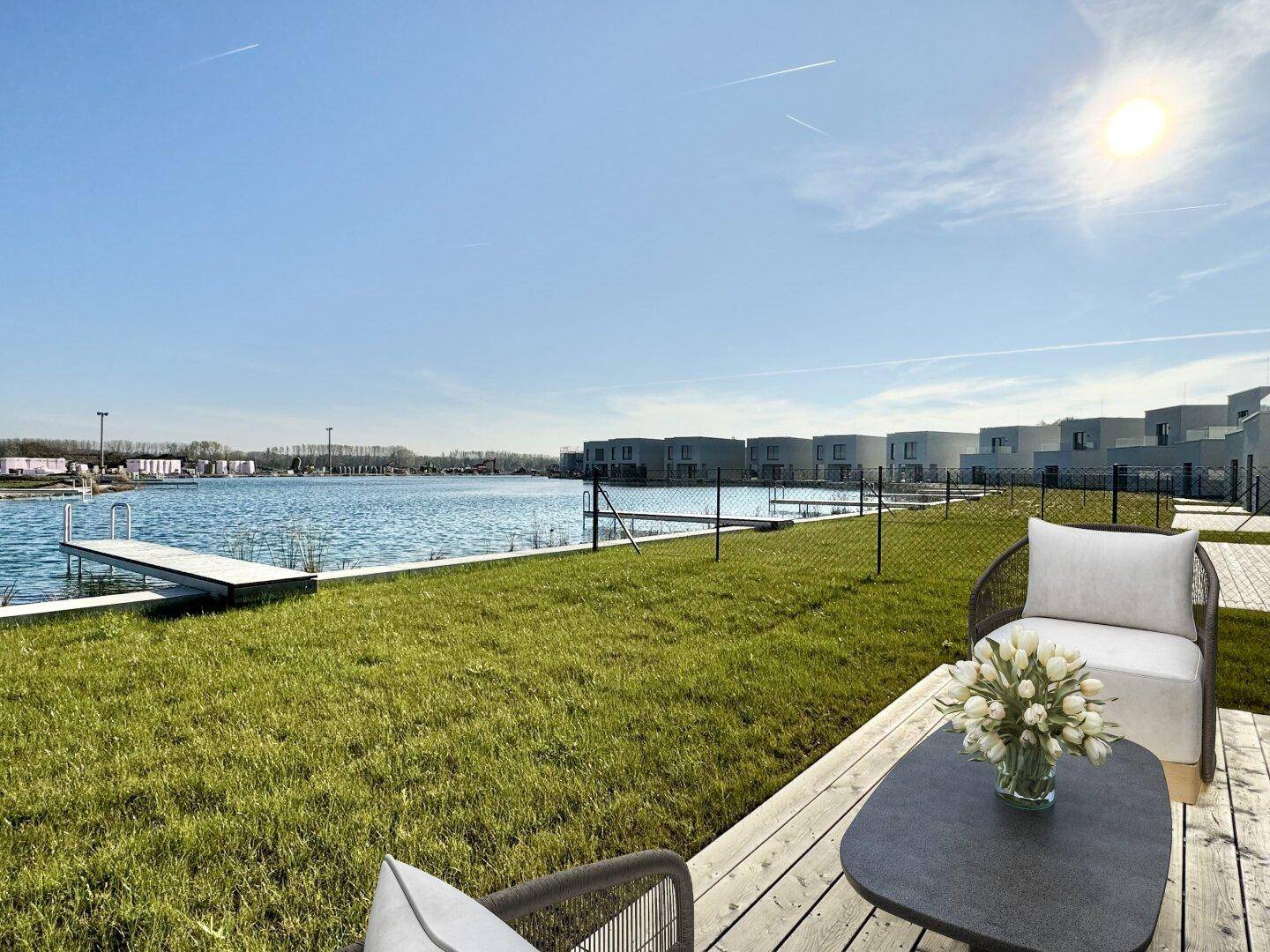 Gemütliche Holzterrasse mit Sitzgelegenheiten und weitem Blick auf den See und die umliegenden Häuser.