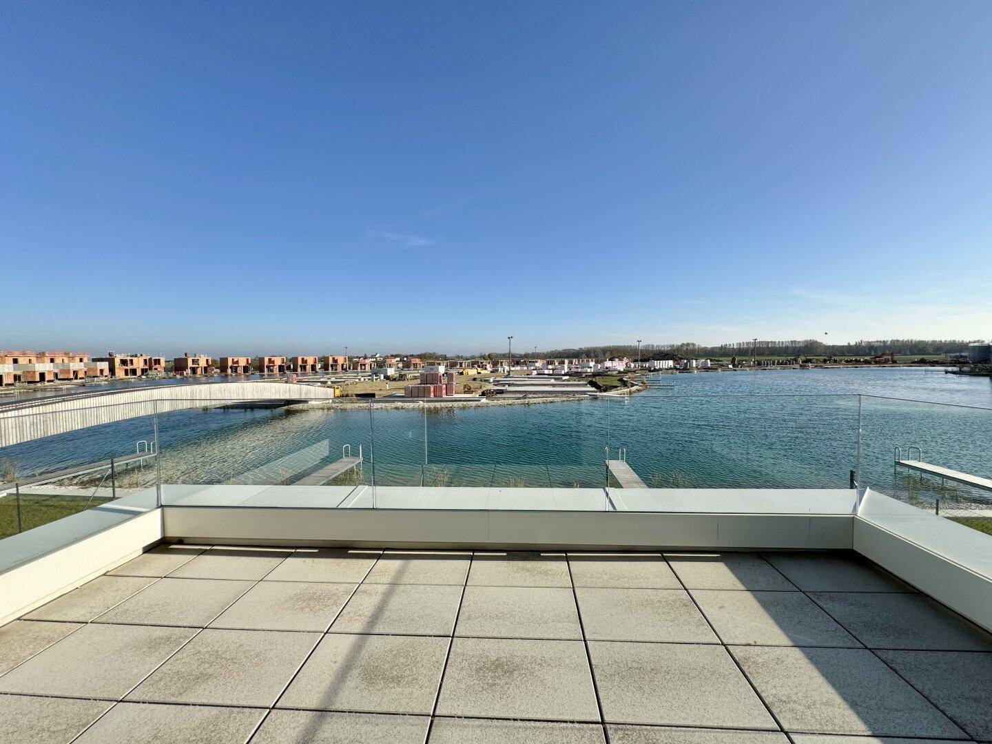 Weitläufige Dachterrasse mit Fliesen und freiem Blick auf die Seenlandschaft und die Umgebung.