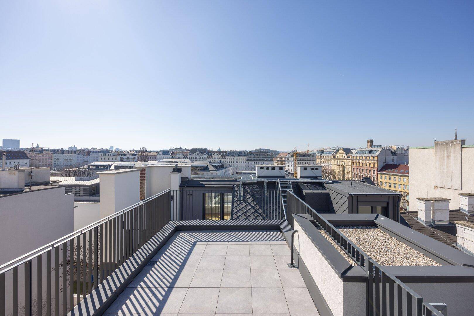 Sonnige Dachterrasse mit modernem Fliesenboden und weitem Blick über die Stadt.
