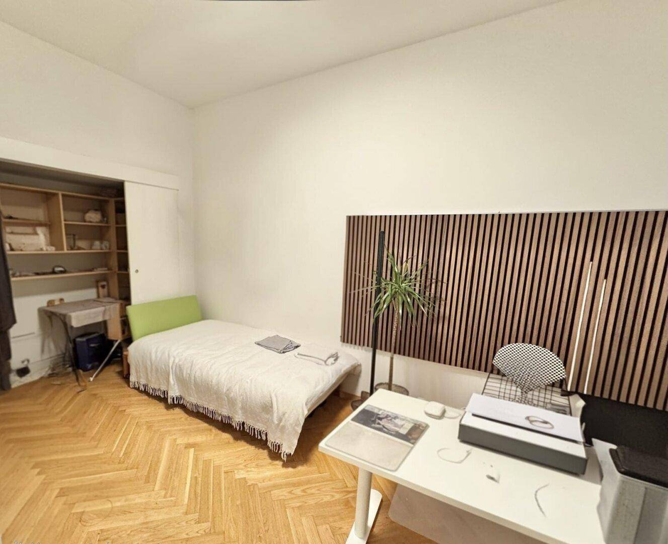 Helles Zimmer mit Parkettboden, Schranknische und modernem Wandpaneel.