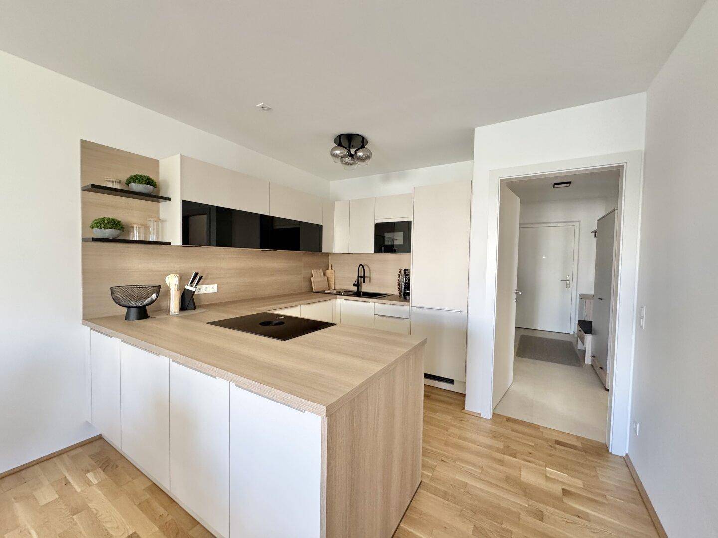 Moderne Einbauküche mit Induktionskochfeld, Holz-Arbeitsplatte und weißen Schränken.
