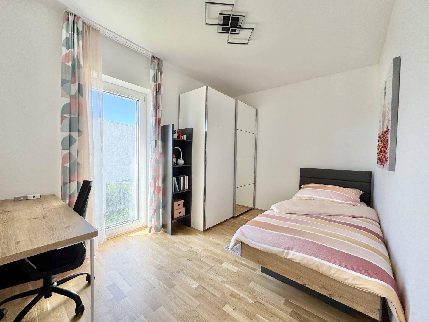 Helles Kinderzimmer mit Einzelbett, Schreibtisch und Zugang zum Balkon.