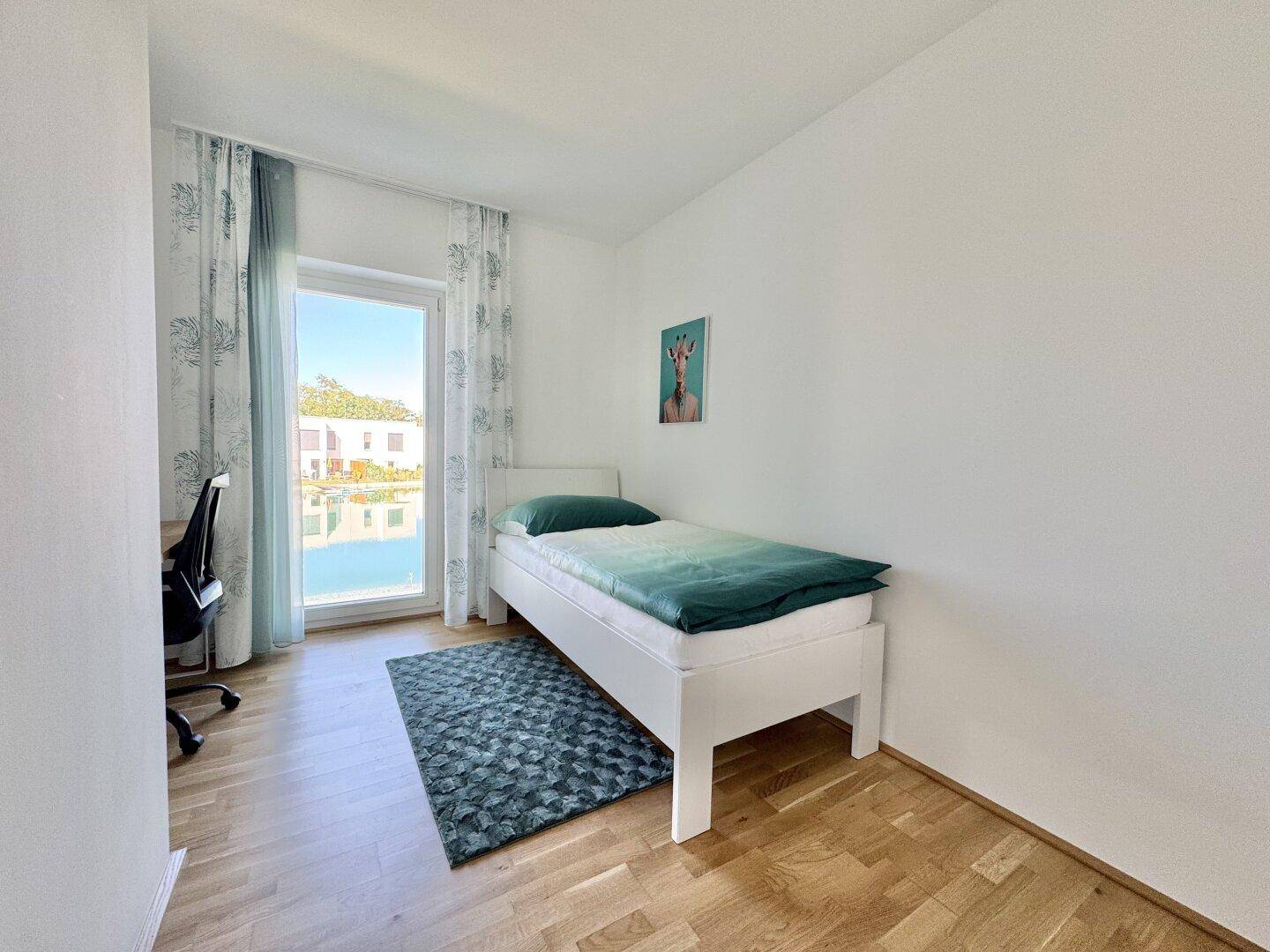 Freundliches Kinderzimmer mit Einzelbett, Schreibtisch und Blick ins Grüne.