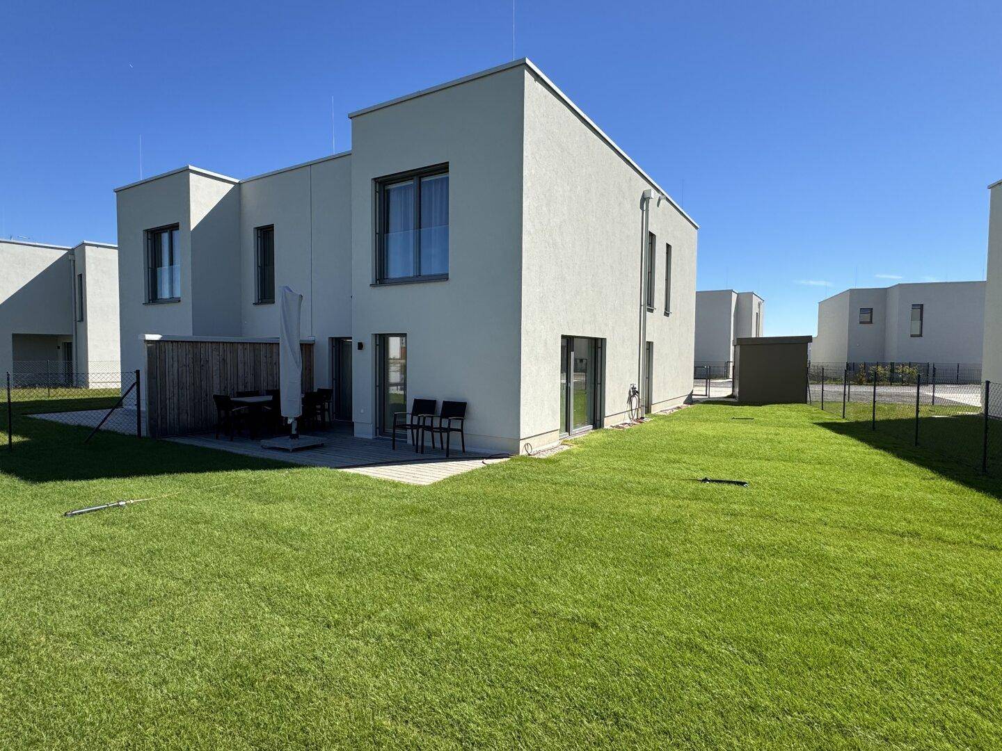 Weitläufiger Gartenbereich mit Rasenfläche und moderner Architektur des Doppelhauses.