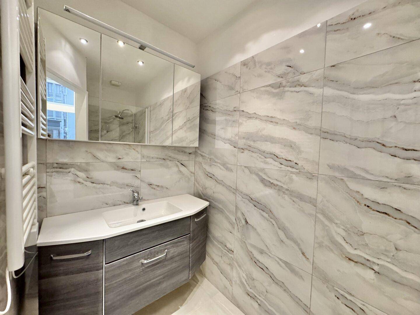 Modernes Badezimmer mit Marmorfliesen, Einzelwaschbecken und Spiegelschrank.