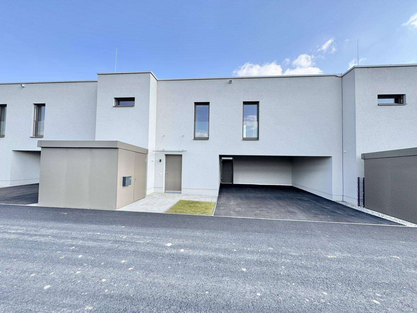Vorderseite moderner Reihenhäuser mit integrierten Carports und Stellplätzen.