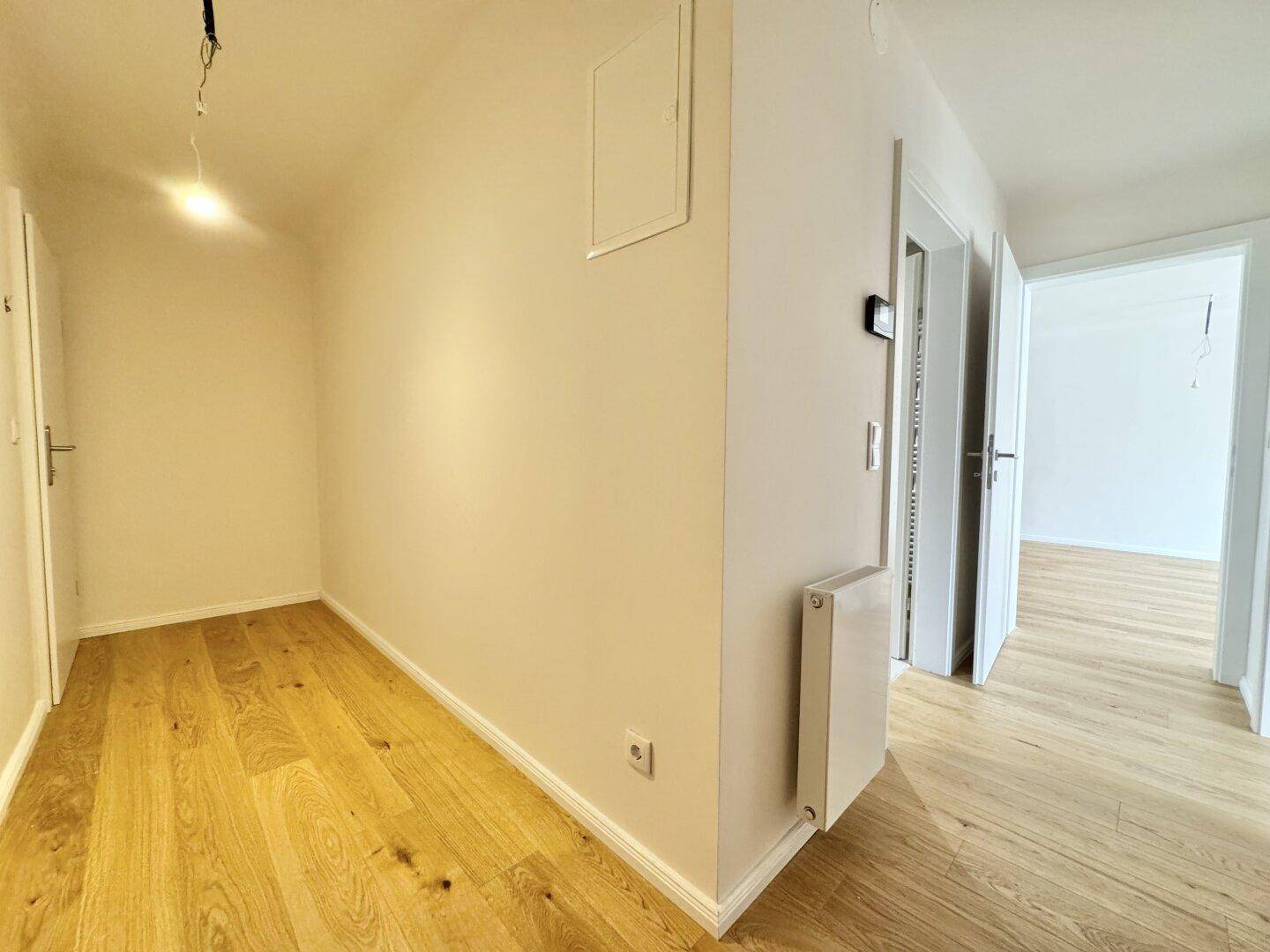 Heller Flur mit Holzboden und Zugang zu verschiedenen Räumen der Wohnung.