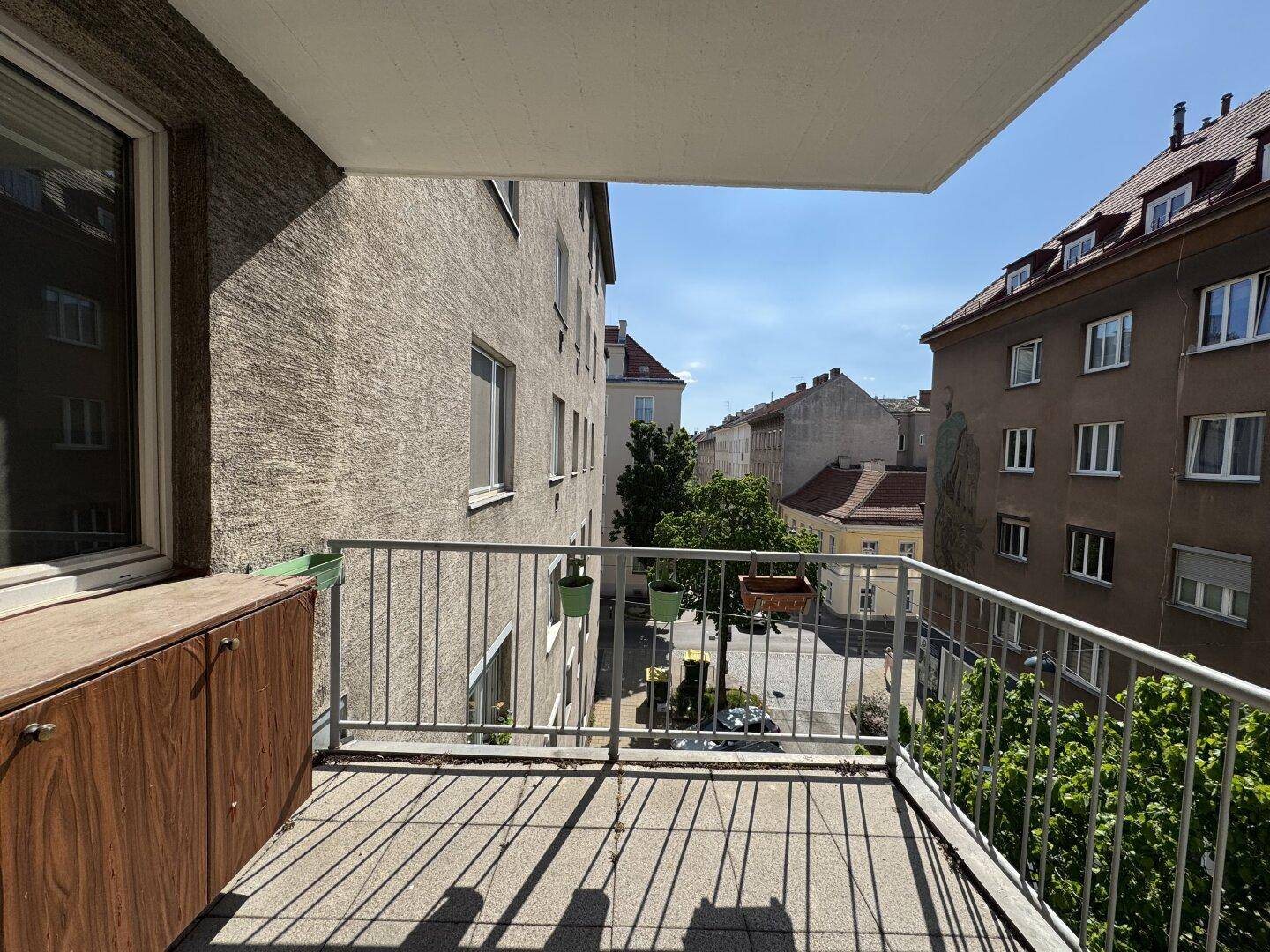 Leerer Balkon mit Metallgeländer und Blick auf die umliegende städtische Bebauung.