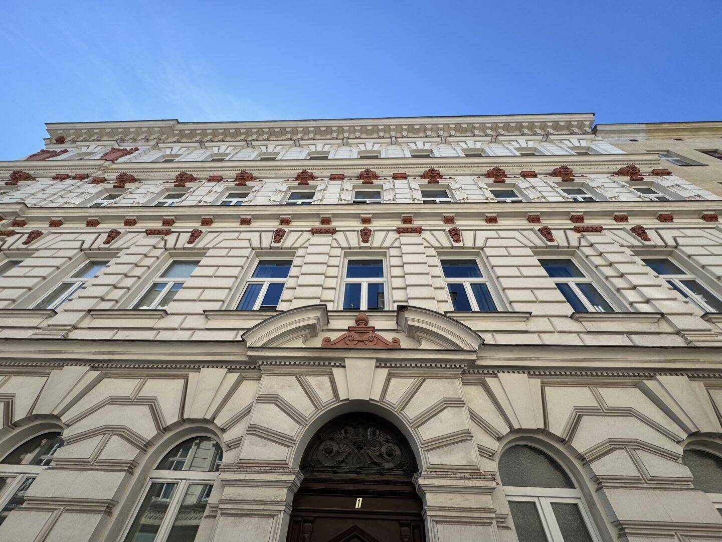 Prächtige Fassade eines Altbaus mit vielen Fenstern und aristokratischen Verzierungen.