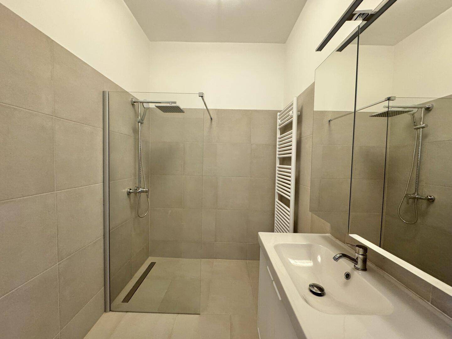 Modernes Badezimmer mit begehbarer Dusche, Einzelwaschbecken und beheiztem Handtuchhalter.