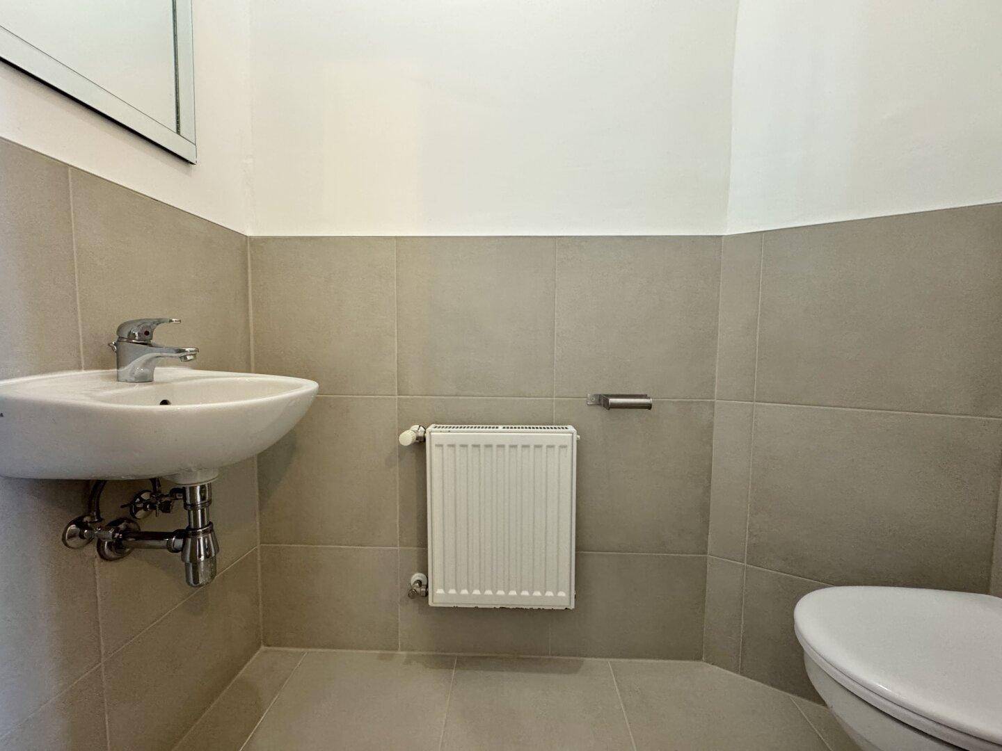 Funktionales Gäste-WC mit kleinem Waschbecken und Toilette, ausgestattet mit Fliesenboden.