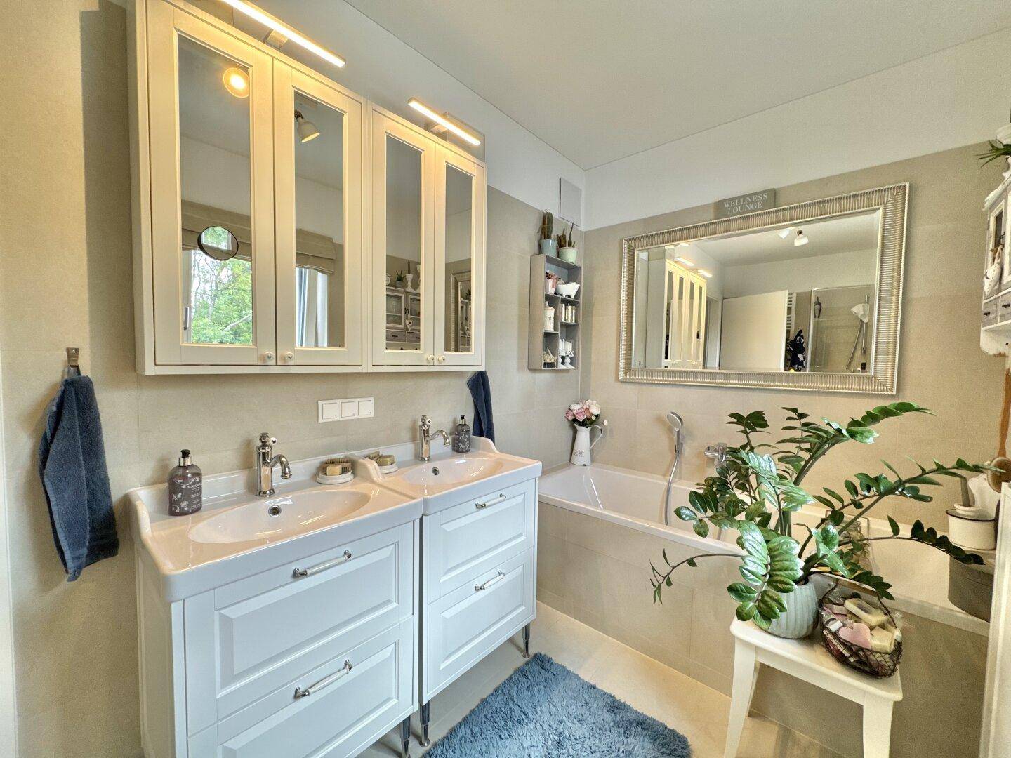 Modernes Badezimmer mit Doppelwaschbecken, Badewanne und Spiegelschränken.