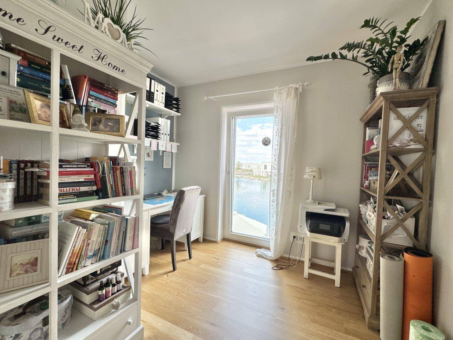 Helles Arbeitszimmer mit Schreibtisch, Bücherregalen und Seeblick.