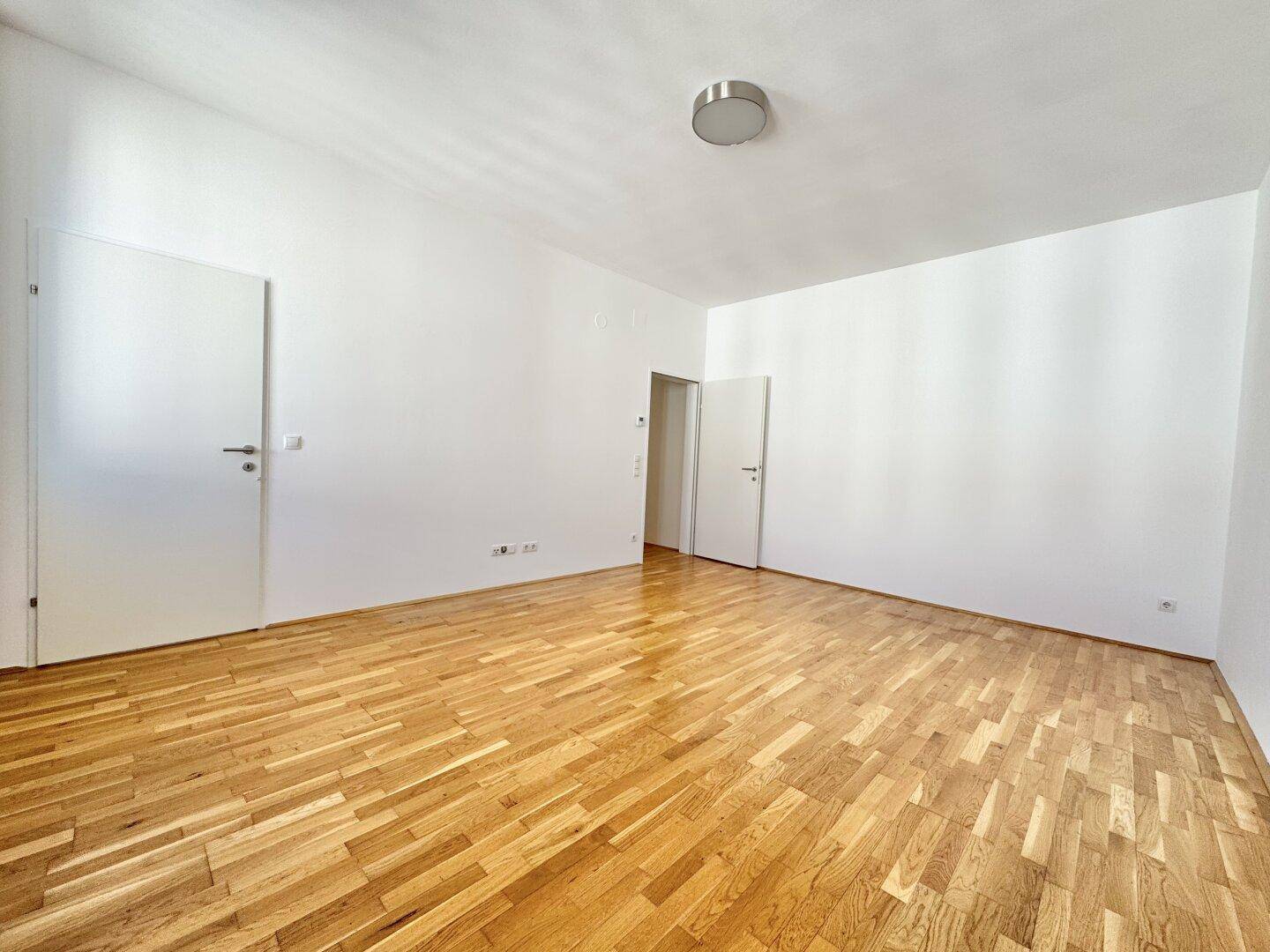 Geräumiges, helles Zimmer mit Parkettboden und weißen Wänden, bietet vielseitige Nutzungsmöglichkeiten.