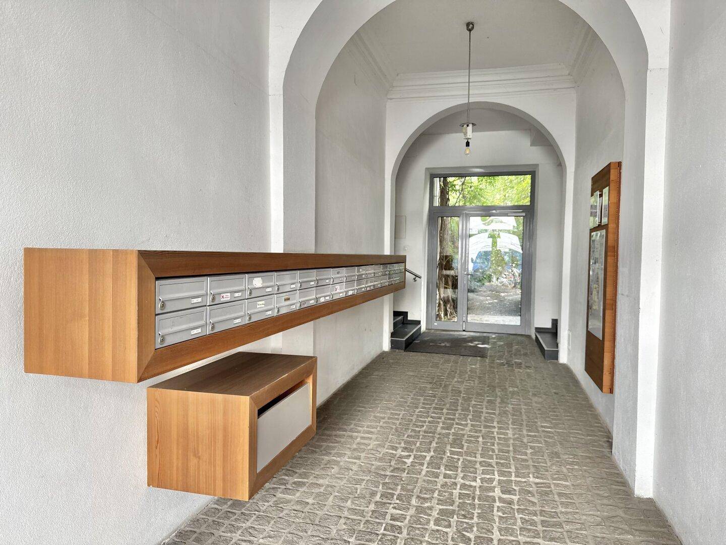 Heller Eingangsbereich mit modernen Briefkästen und historischem Charme, führt zum Treppenhaus.