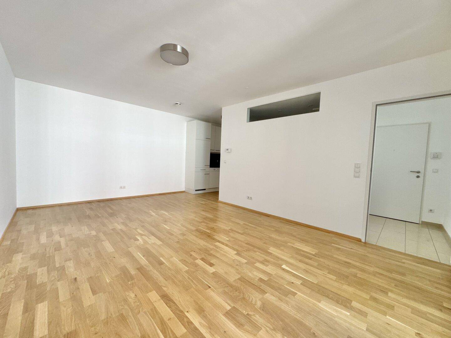 Geräumiger, heller Wohnbereich mit Parkettboden und Zugang zu weiteren Räumen.