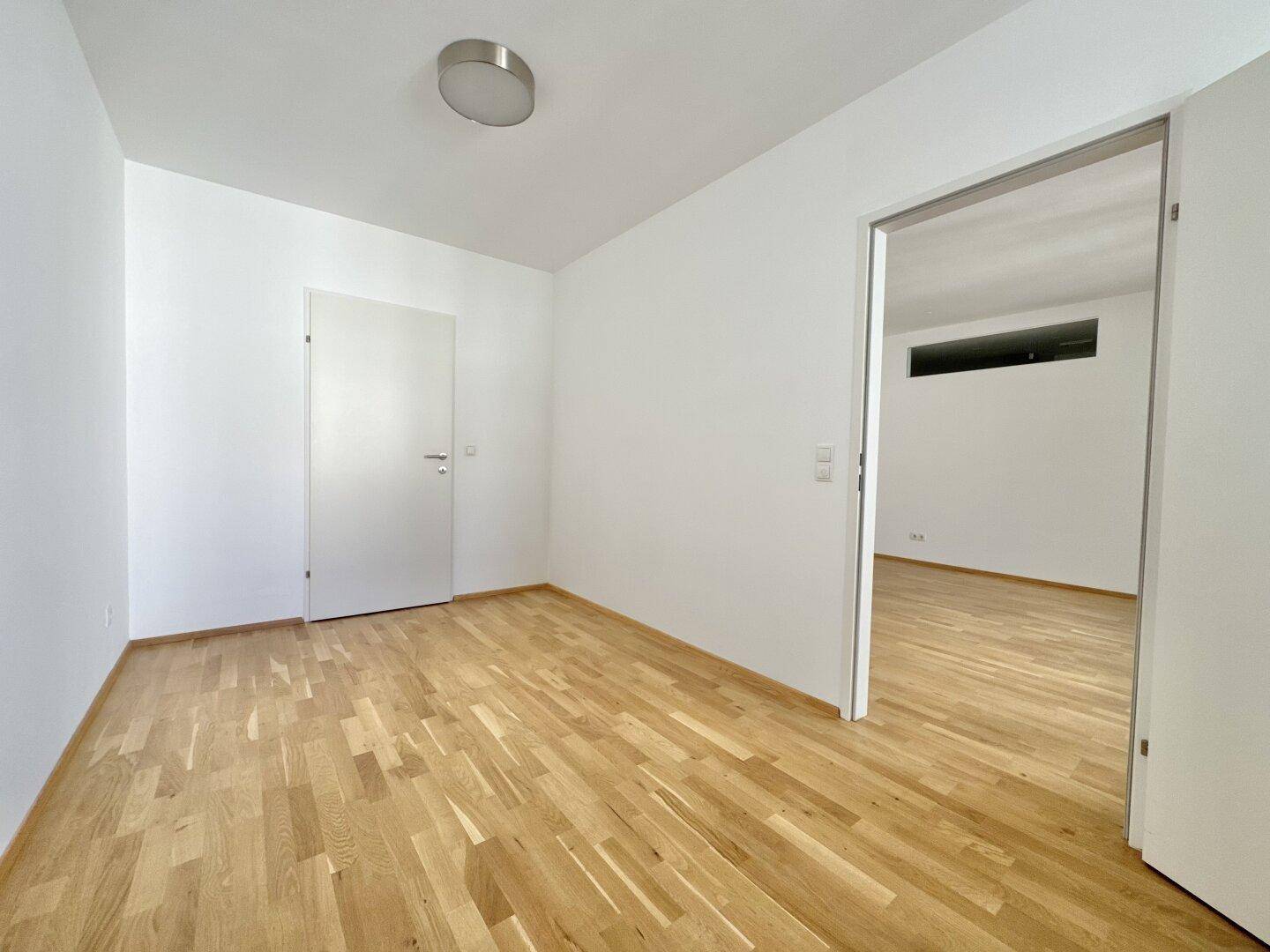 Helles Zimmer mit Parkettboden und weiß gestrichenen Wänden, bereit zur individuellen Gestaltung.