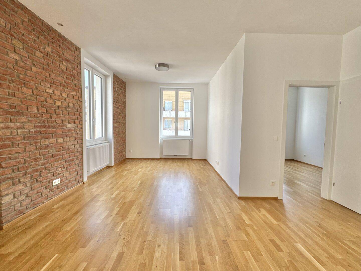 Geräumiges Zimmer mit Holzboden, weißen Wänden und einem Blick auf die gegenüberliegende Tür.