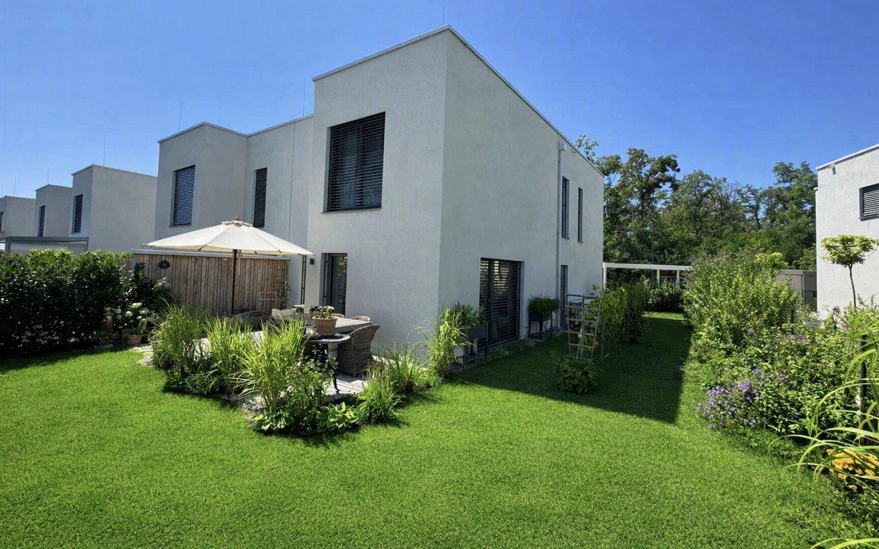 Moderne Architektur des Hauses mit großem, gepflegtem Garten und einer einladenden Terrasse.