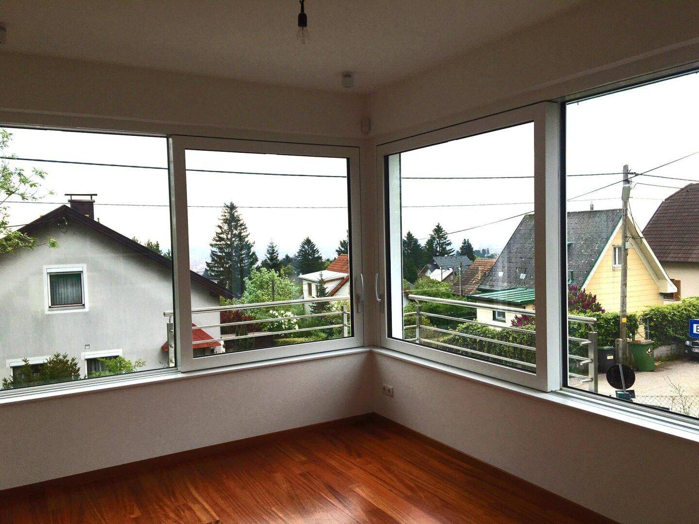 Lichtdurchfluteter Raum mit großen Eckfenstern und weitem Blick über die Nachbarschaft.