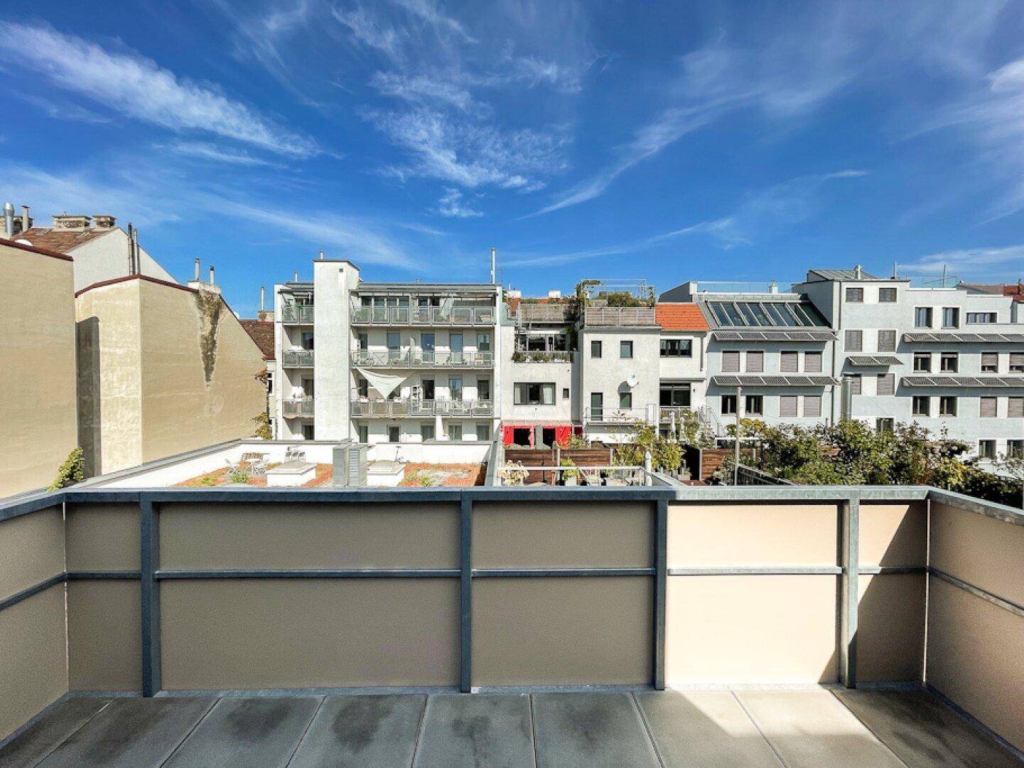 Balkon mit Blick auf die umliegenden Gebäude und den blauen Himmel.