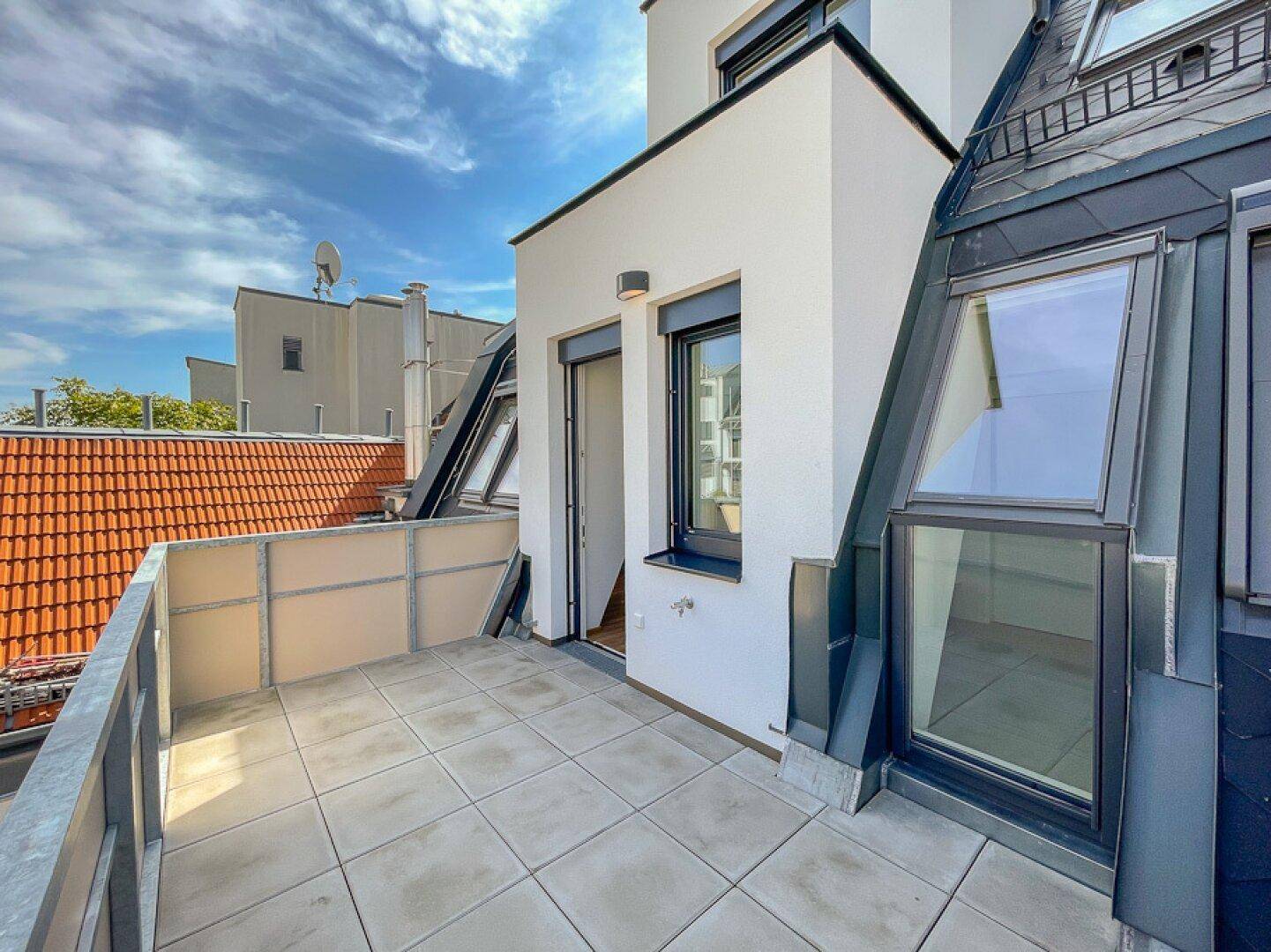 Geräumige Dachterrasse mit Fliesenboden und Blick auf die umliegenden Dächer.