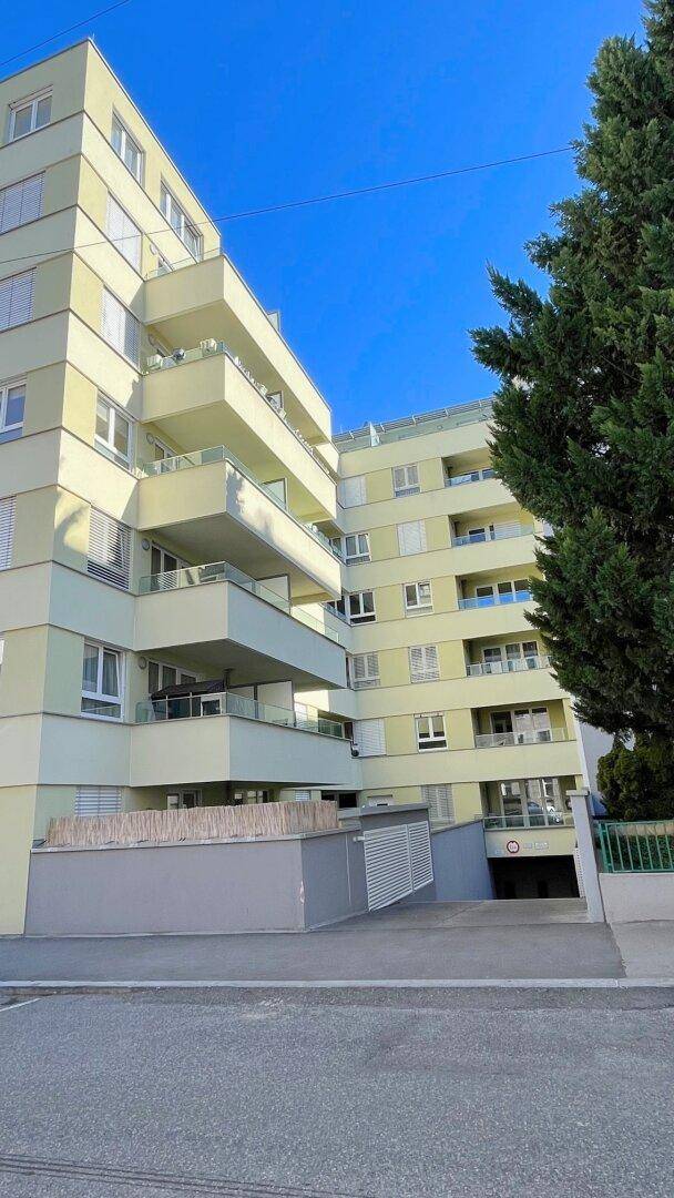 Modernes Mehrfamilienhaus mit zahlreichen Balkonen und Tiefgaragenzufahrt.