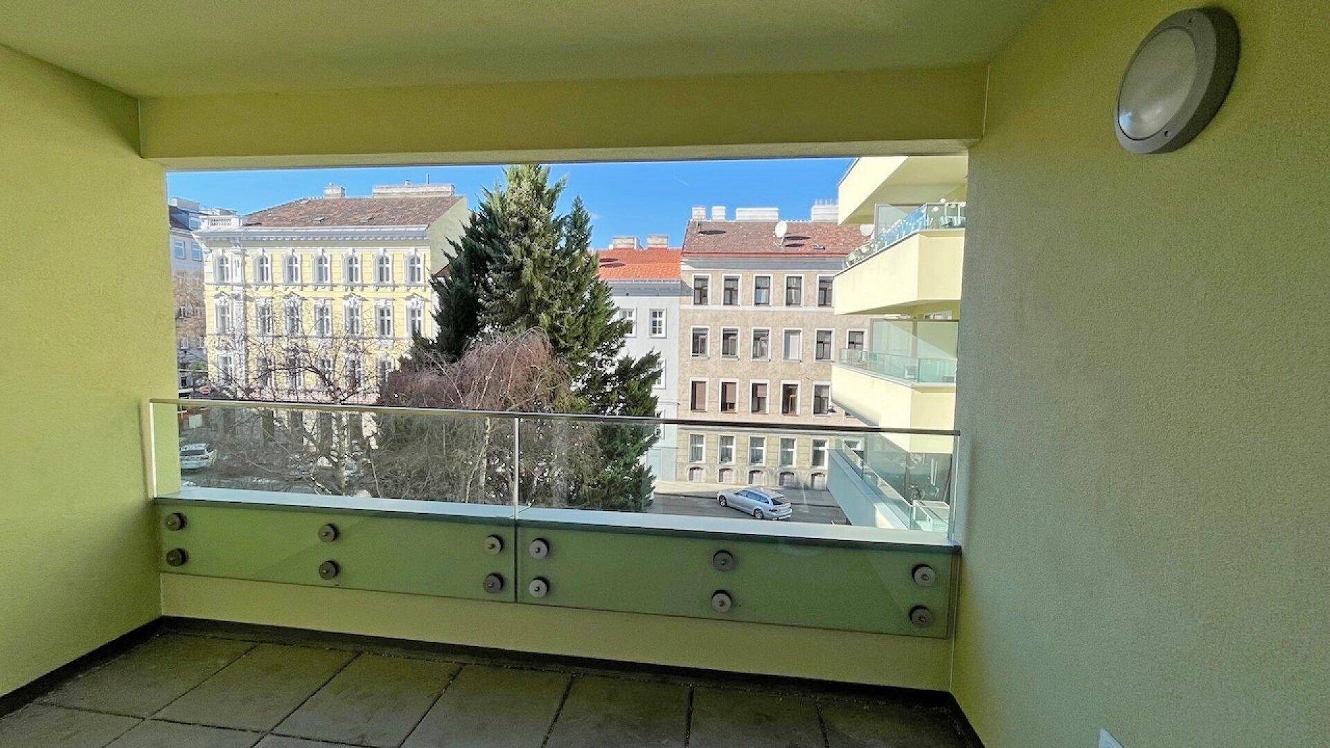 Geräumiger Balkon mit moderner Glasbrüstung und Blick auf die städtische Umgebung.