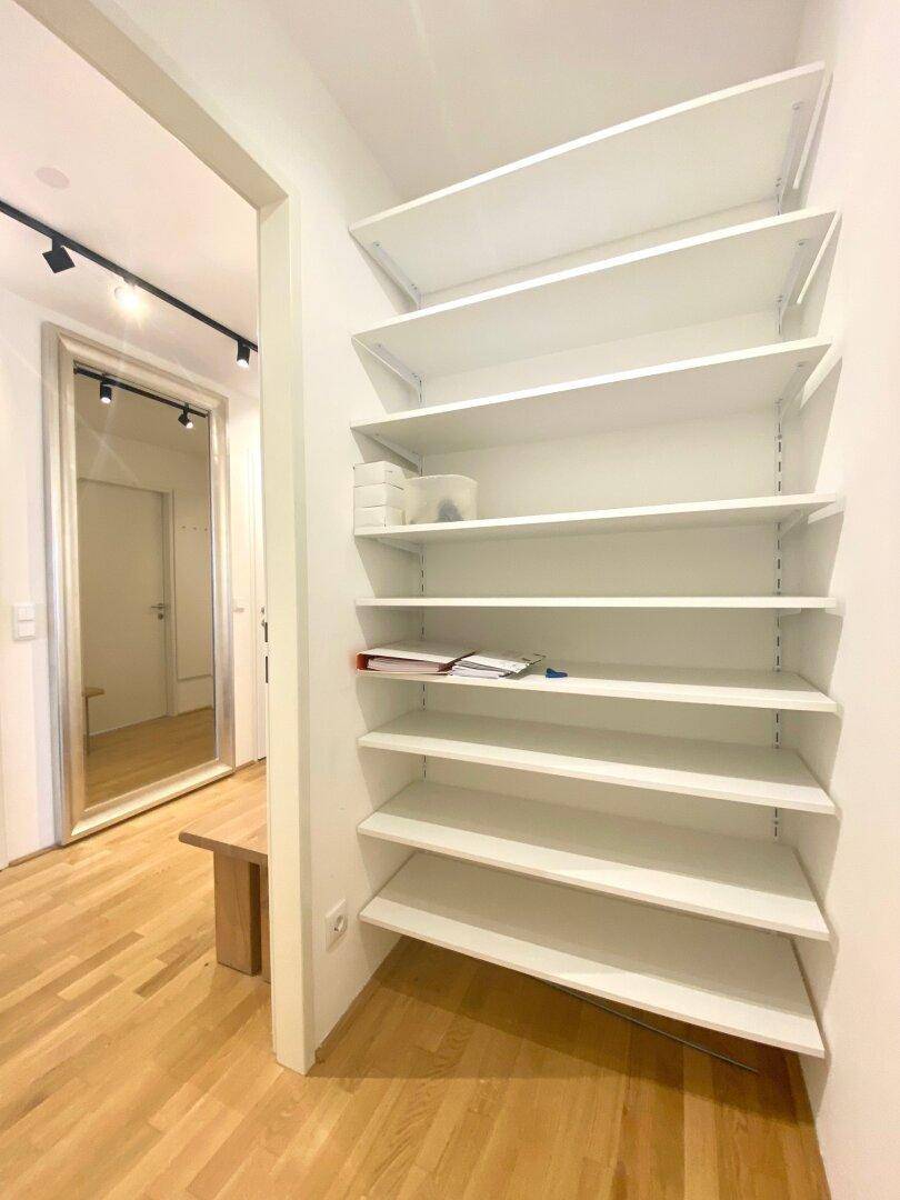 Heller Flur mit praktischen Regalen für zusätzlichen Stauraum und Holzboden.