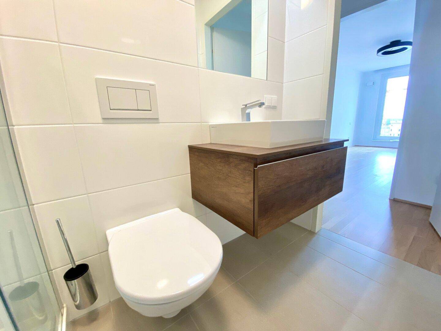 Modernes WC mit wandhängender Toilette, Waschbecken und Holzunterschrank.